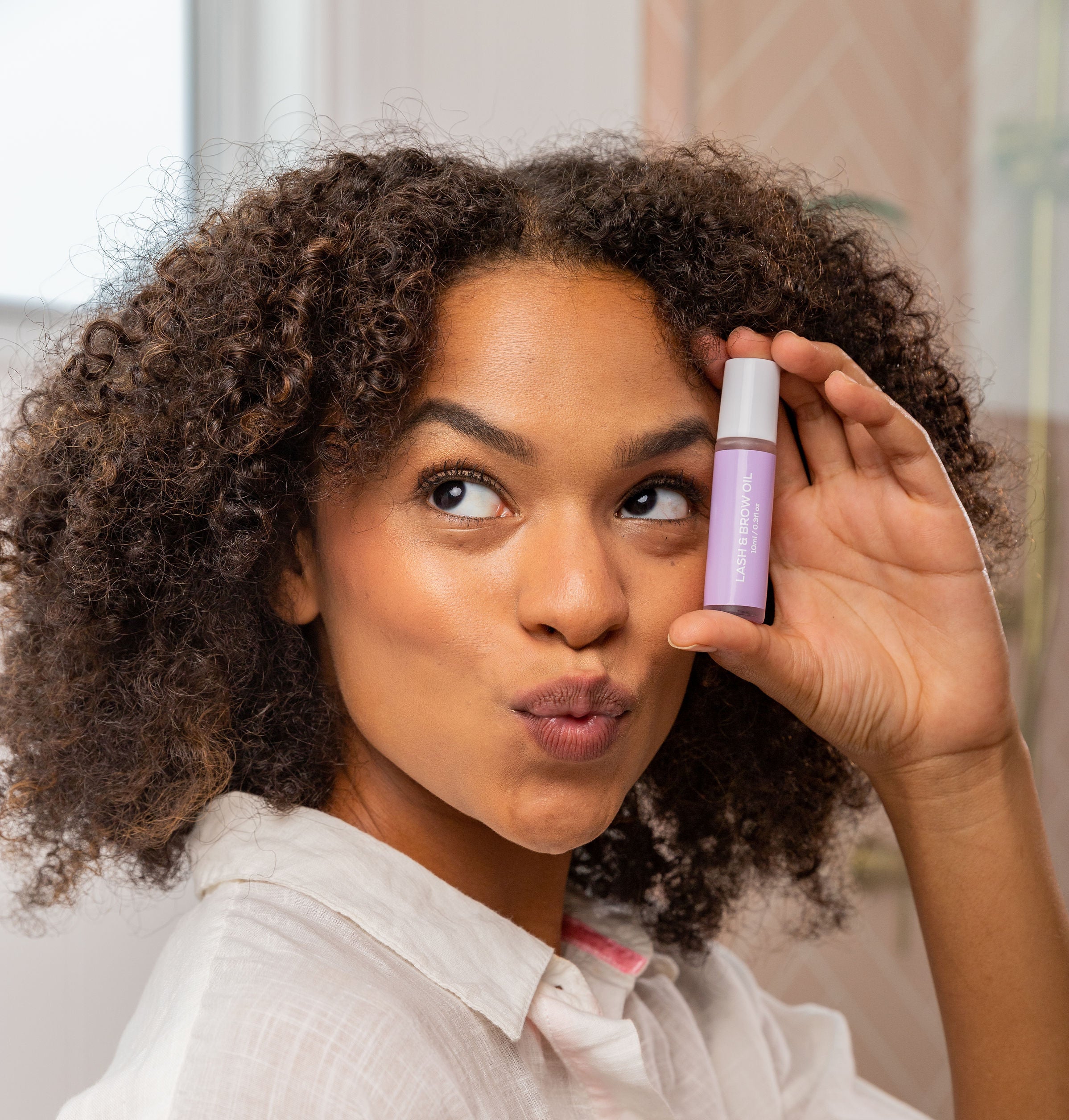 BodyBlendz lash and brow growth serum held by model, enhancing fuller thicker lashes and brows with nourishing formula