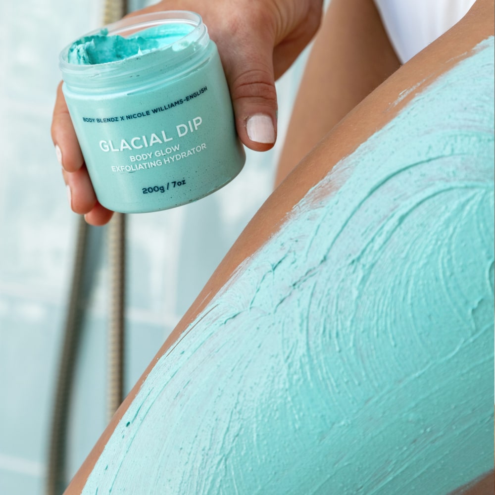 BodyBlendz Glacial Dip Body Glow Exfoliating Hydrator applied on skin showing aqua clay texture with jar held in hand for smooth glowing skin