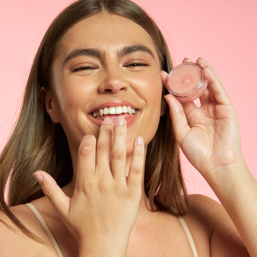 Smiling woman using BodyBlendz lip scrub to exfoliate lips for a smooth soft hydrated finish