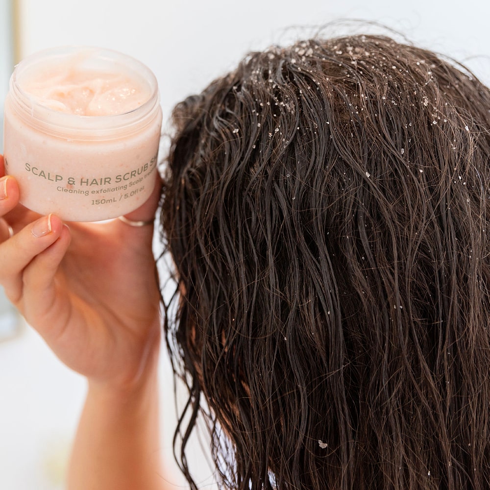 Woman applying BodyBlendz scalp and hair scrub shampoo to wet hair, exfoliating scalp to remove buildup and flakes for healthy hair growth