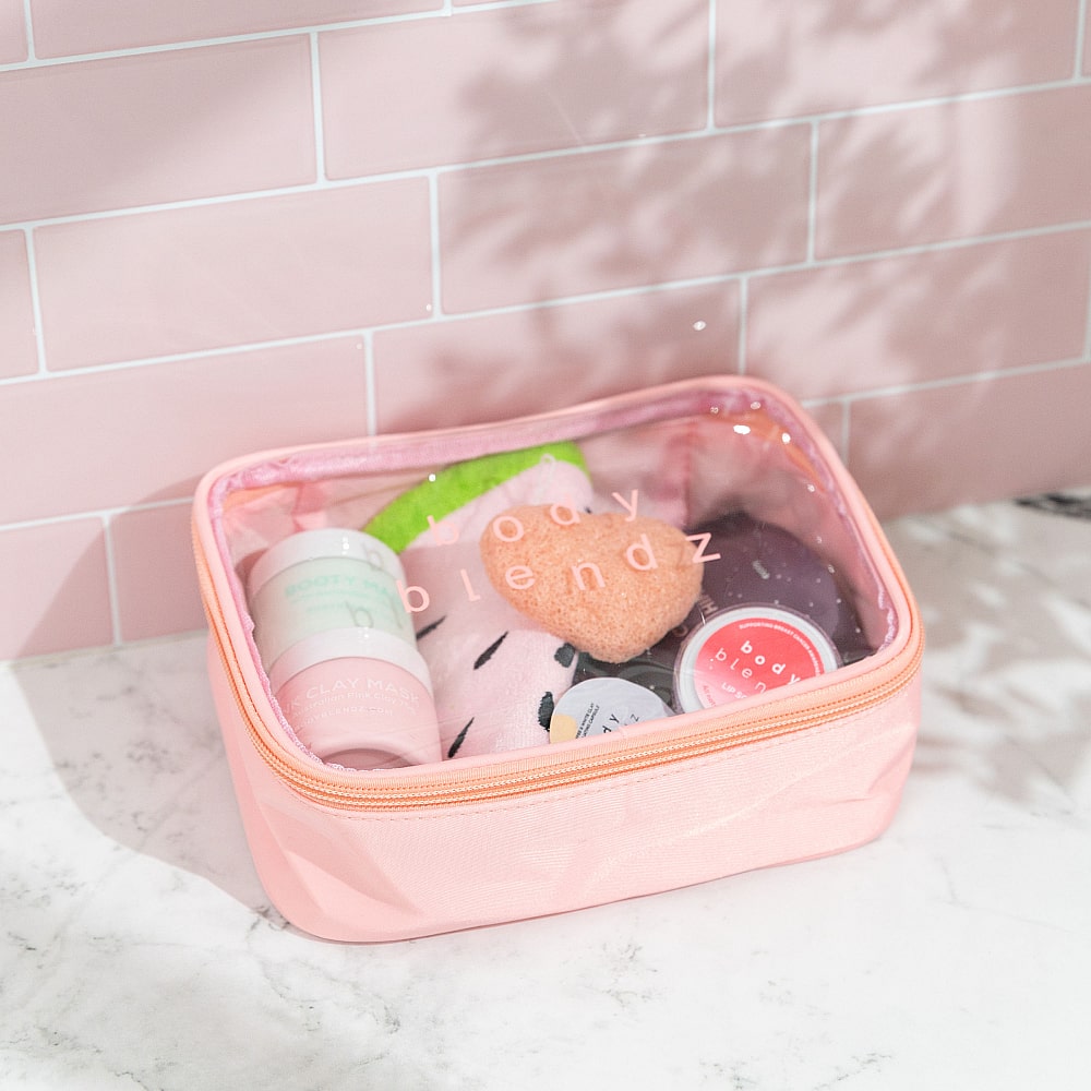 BodyBlendz skincare essentials in pink cosmetic bag featuring konjac sponge, facial mask, and beauty products for travel-friendly skincare routine