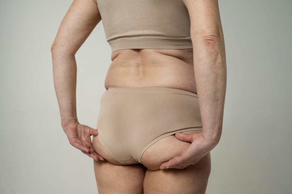 Woman showing natural skin texture around the hips and buttocks in neutral underwear